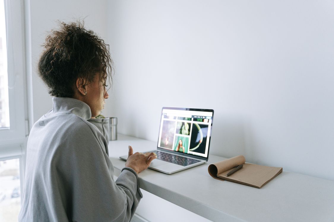 Woman in casual clothing working on a laptop at a bright desk.